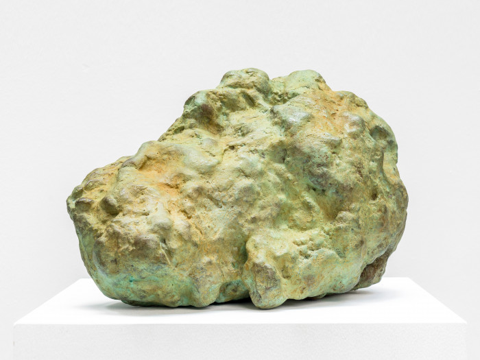 The sculpture depicts a sleeping head with a gree patina. sculpted by William Tucker